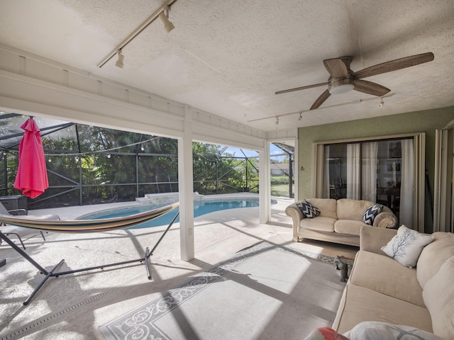 sunroom / solarium with ceiling fan, a pool, and rail lighting