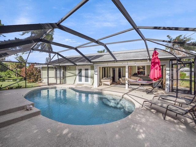 view of swimming pool with glass enclosure, a patio, and french doors