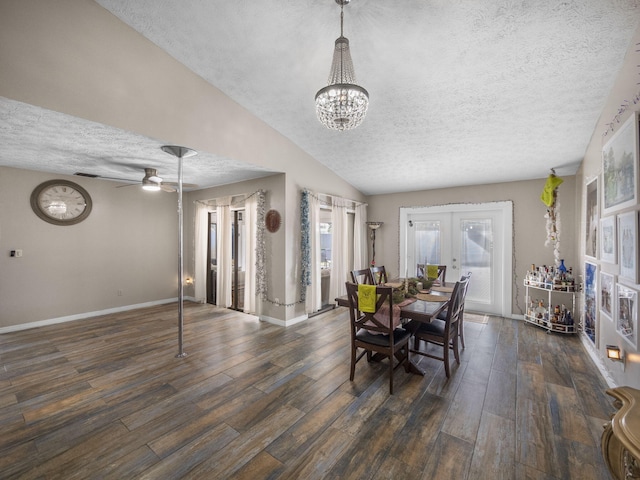 dining room featuring dark wood-type flooring, french doors, ceiling fan with notable chandelier, vaulted ceiling, and a textured ceiling