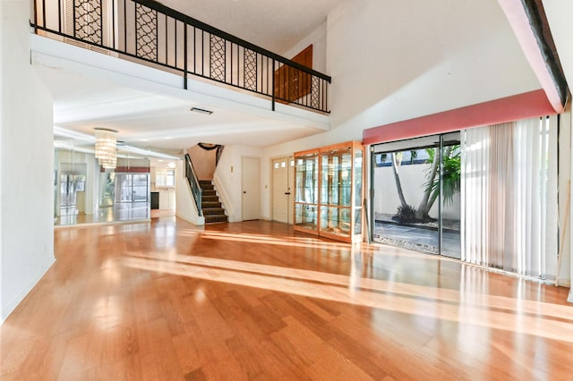 interior space featuring a wealth of natural light, an inviting chandelier, a high ceiling, and hardwood / wood-style flooring