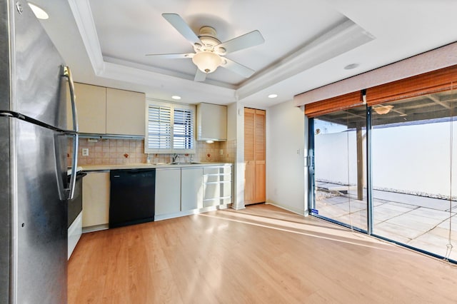 kitchen featuring black dishwasher, a tray ceiling, stainless steel refrigerator, and light hardwood / wood-style floors