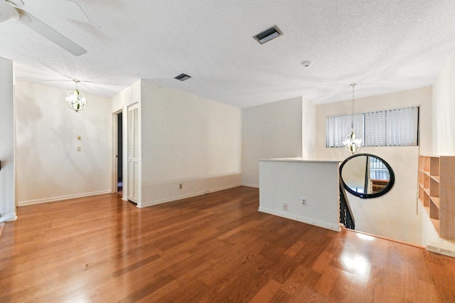 unfurnished living room featuring wood-type flooring, a textured ceiling, and a notable chandelier