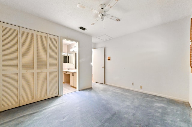 unfurnished bedroom with carpet, a textured ceiling, connected bathroom, and ceiling fan