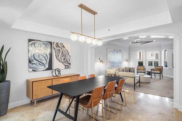 dining area with a raised ceiling, ornamental molding, and a notable chandelier