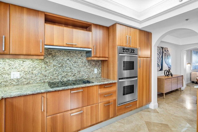 kitchen with backsplash, black electric stovetop, light stone countertops, ornamental molding, and stainless steel double oven