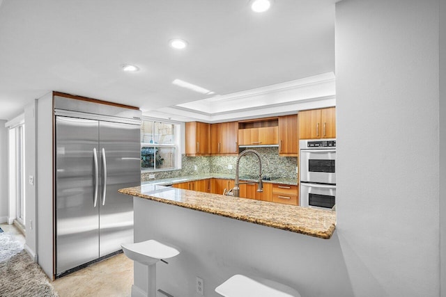 kitchen with decorative backsplash, ornamental molding, light stone counters, kitchen peninsula, and stainless steel appliances