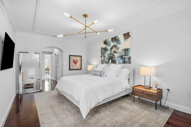 bedroom featuring dark hardwood / wood-style flooring, ornamental molding, and an inviting chandelier