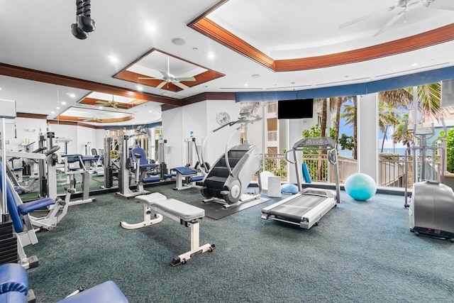 exercise room with a tray ceiling, ceiling fan, and ornamental molding