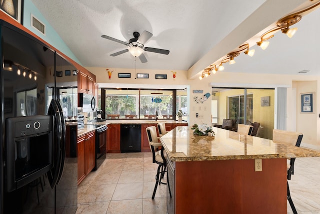 kitchen with a kitchen breakfast bar, light stone counters, ceiling fan, and black appliances