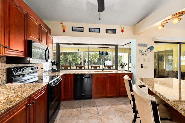 kitchen featuring sink, backsplash, light stone counters, and black appliances