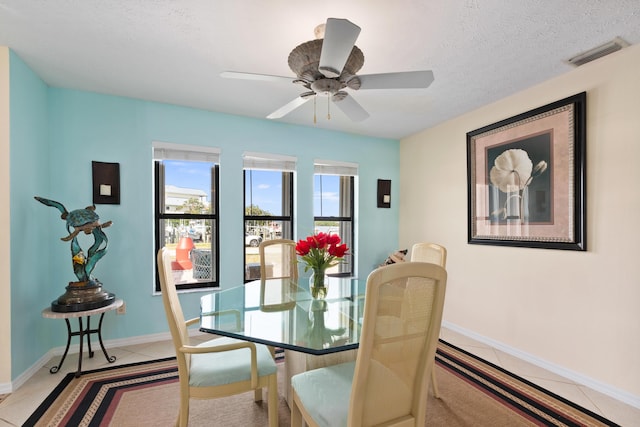 dining space with ceiling fan, light tile patterned floors, and a textured ceiling