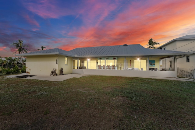 back house at dusk with a yard and a patio