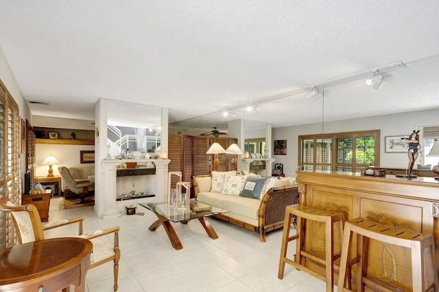 living room with a textured ceiling, ceiling fan, light tile patterned floors, and track lighting