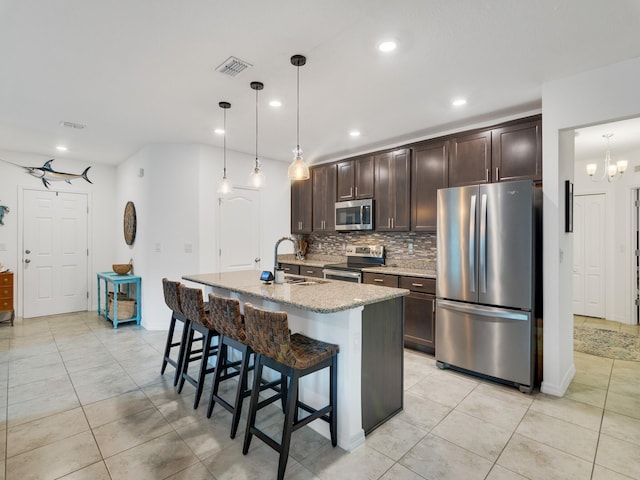 kitchen with sink, hanging light fixtures, stainless steel appliances, an island with sink, and dark brown cabinets