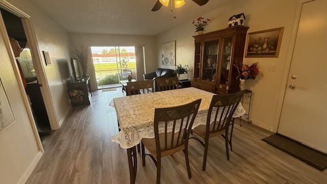 dining area with ceiling fan, hardwood / wood-style floors, and a textured ceiling