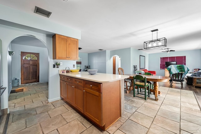 kitchen with ceiling fan, kitchen peninsula, and hanging light fixtures