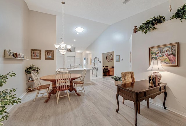 dining room featuring high vaulted ceiling, light hardwood / wood-style floors, and an inviting chandelier