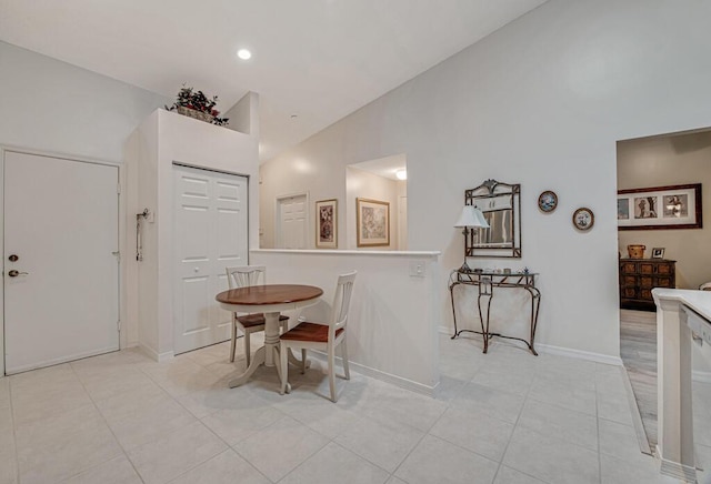 dining area featuring high vaulted ceiling and light tile patterned flooring