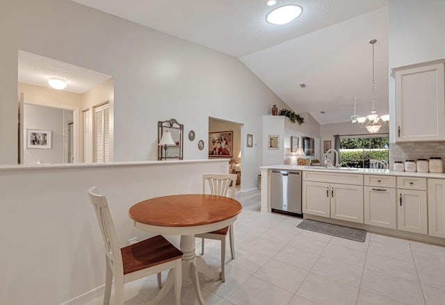 kitchen with stainless steel dishwasher, a textured ceiling, sink, high vaulted ceiling, and hanging light fixtures