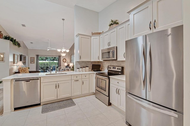 kitchen with sink, stainless steel appliances, kitchen peninsula, pendant lighting, and light tile patterned floors