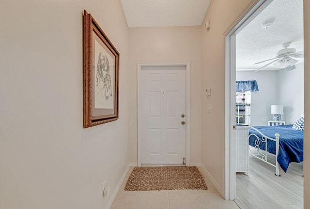 entryway with ceiling fan, light tile patterned floors, and a textured ceiling