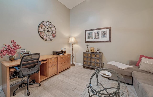 office area with high vaulted ceiling and light hardwood / wood-style flooring