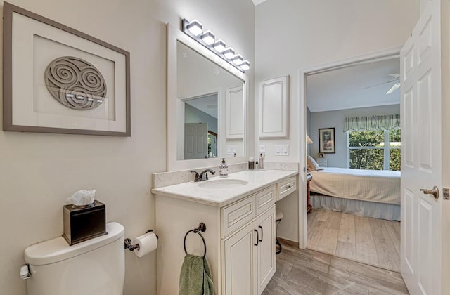 bathroom featuring wood-type flooring, vanity, toilet, and ceiling fan