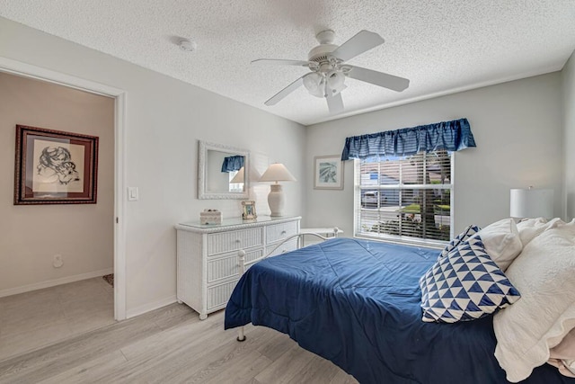 bedroom featuring ceiling fan, light hardwood / wood-style flooring, and a textured ceiling