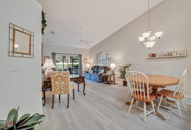 dining area featuring ceiling fan with notable chandelier, high vaulted ceiling, and light hardwood / wood-style flooring