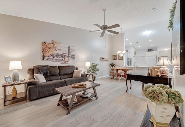 living room with ceiling fan, a textured ceiling, and light wood-type flooring