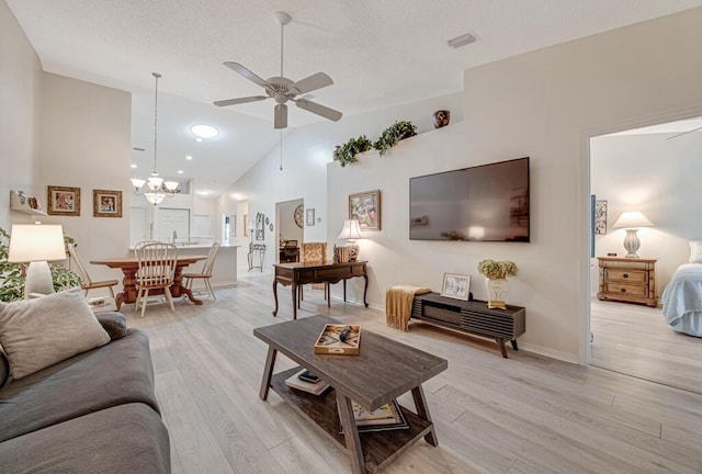 living room featuring ceiling fan with notable chandelier, light hardwood / wood-style floors, and high vaulted ceiling