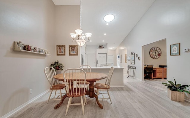 dining room with high vaulted ceiling, a notable chandelier, and light wood-type flooring