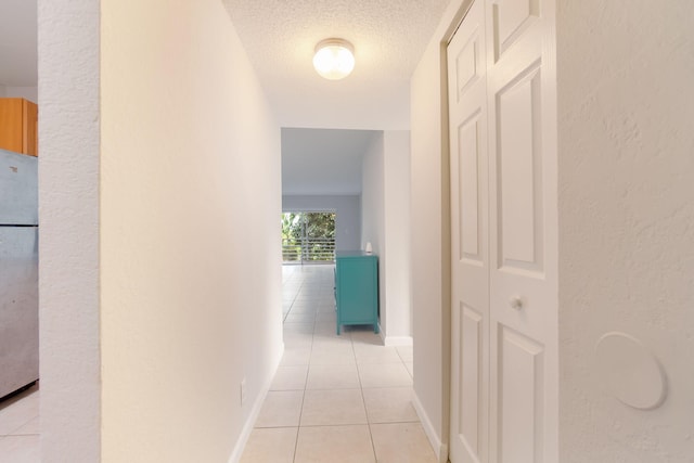 hall featuring light tile patterned flooring and a textured ceiling