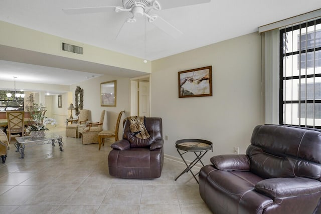 tiled living room with ceiling fan with notable chandelier