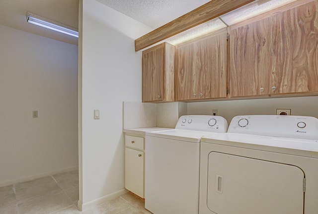 laundry area with washer and clothes dryer, cabinets, light tile patterned floors, and a textured ceiling