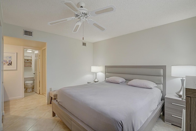 bedroom with connected bathroom, ceiling fan, light tile patterned floors, and a textured ceiling