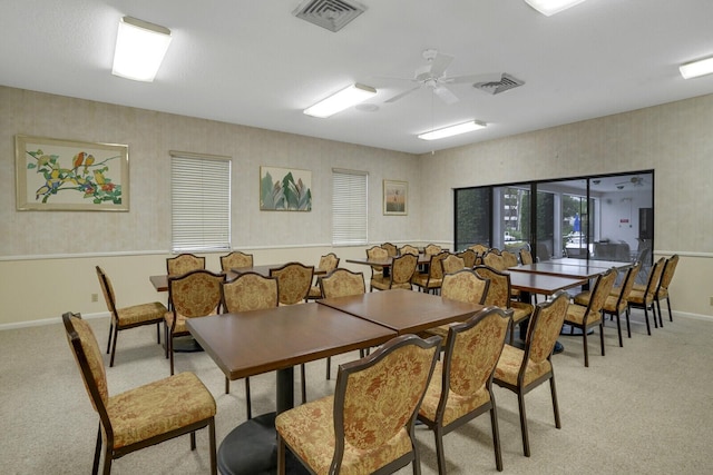 carpeted dining room with ceiling fan