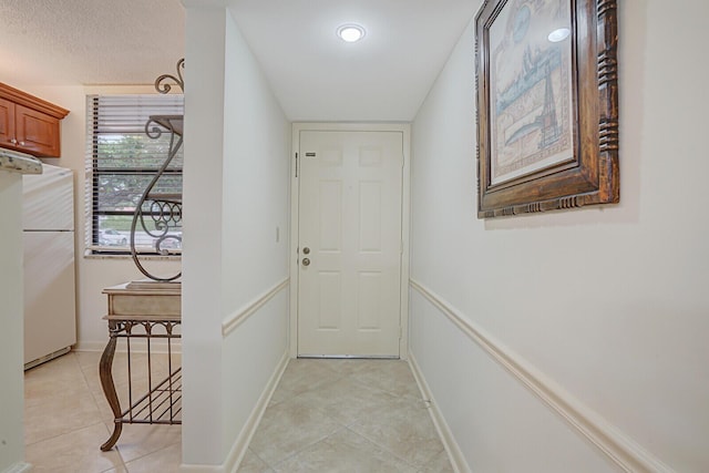 doorway with light tile patterned floors and a textured ceiling