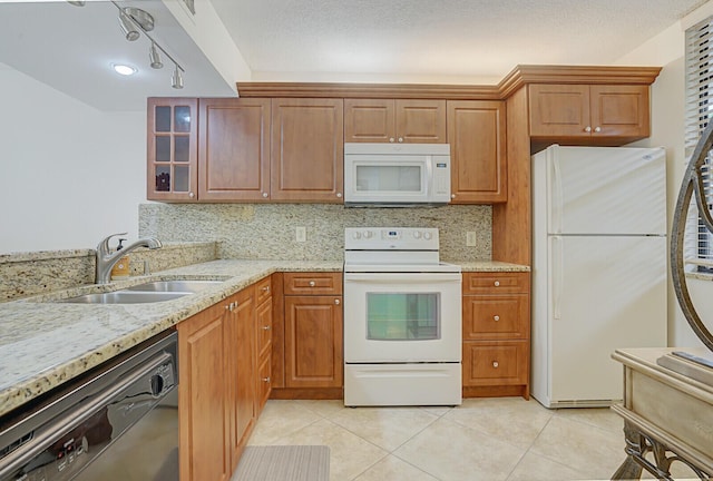 kitchen featuring decorative backsplash, sink, light stone countertops, and white appliances