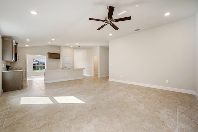 unfurnished living room featuring light tile patterned floors, vaulted ceiling, ceiling fan, and sink