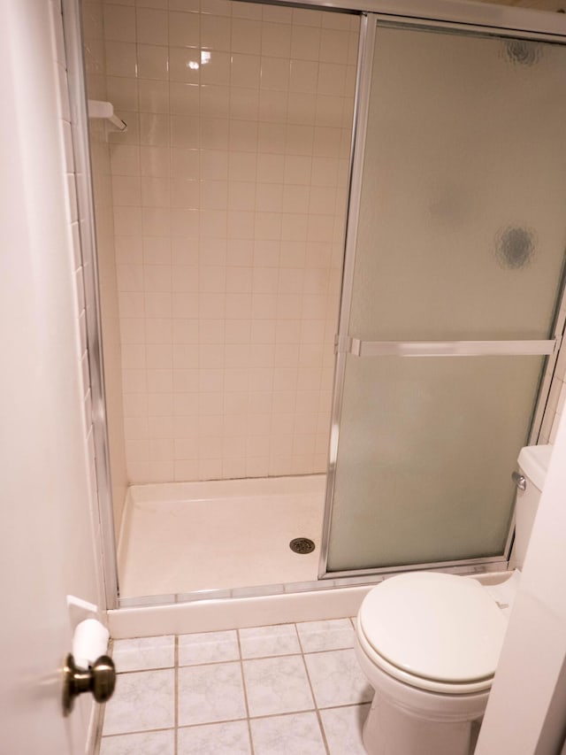 bathroom with tile patterned floors, a shower with shower door, and toilet