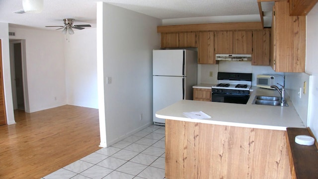 kitchen featuring white appliances, sink, ceiling fan, light hardwood / wood-style floors, and kitchen peninsula