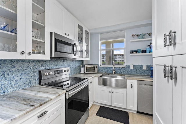 kitchen with decorative backsplash, stainless steel appliances, sink, light hardwood / wood-style flooring, and white cabinetry