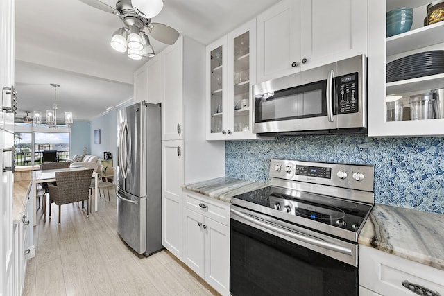 kitchen featuring white cabinets, stainless steel appliances, light stone counters, and light hardwood / wood-style floors