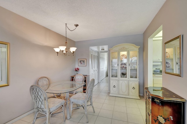 tiled dining room featuring a chandelier and a textured ceiling