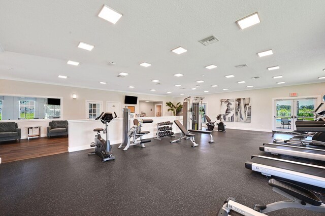 exercise room with french doors, a textured ceiling, and crown molding