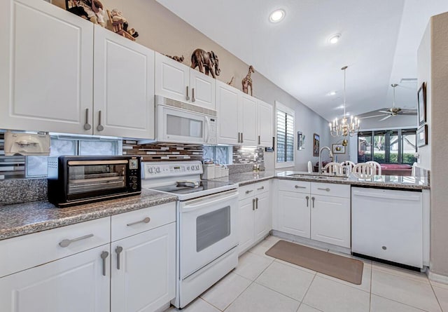 kitchen with white appliances, backsplash, sink, vaulted ceiling, and white cabinetry