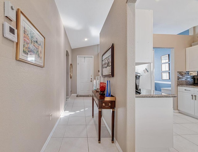 hallway featuring light tile patterned floors and lofted ceiling