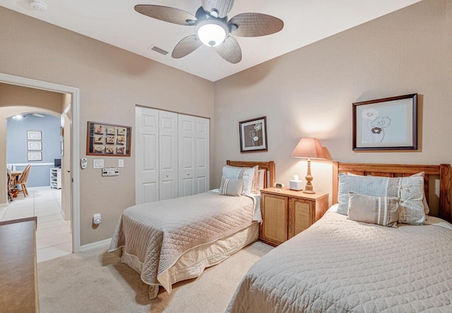 bedroom with a closet, ceiling fan, and light colored carpet