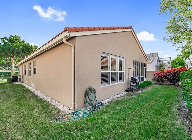 view of home's exterior with a lawn and central AC unit